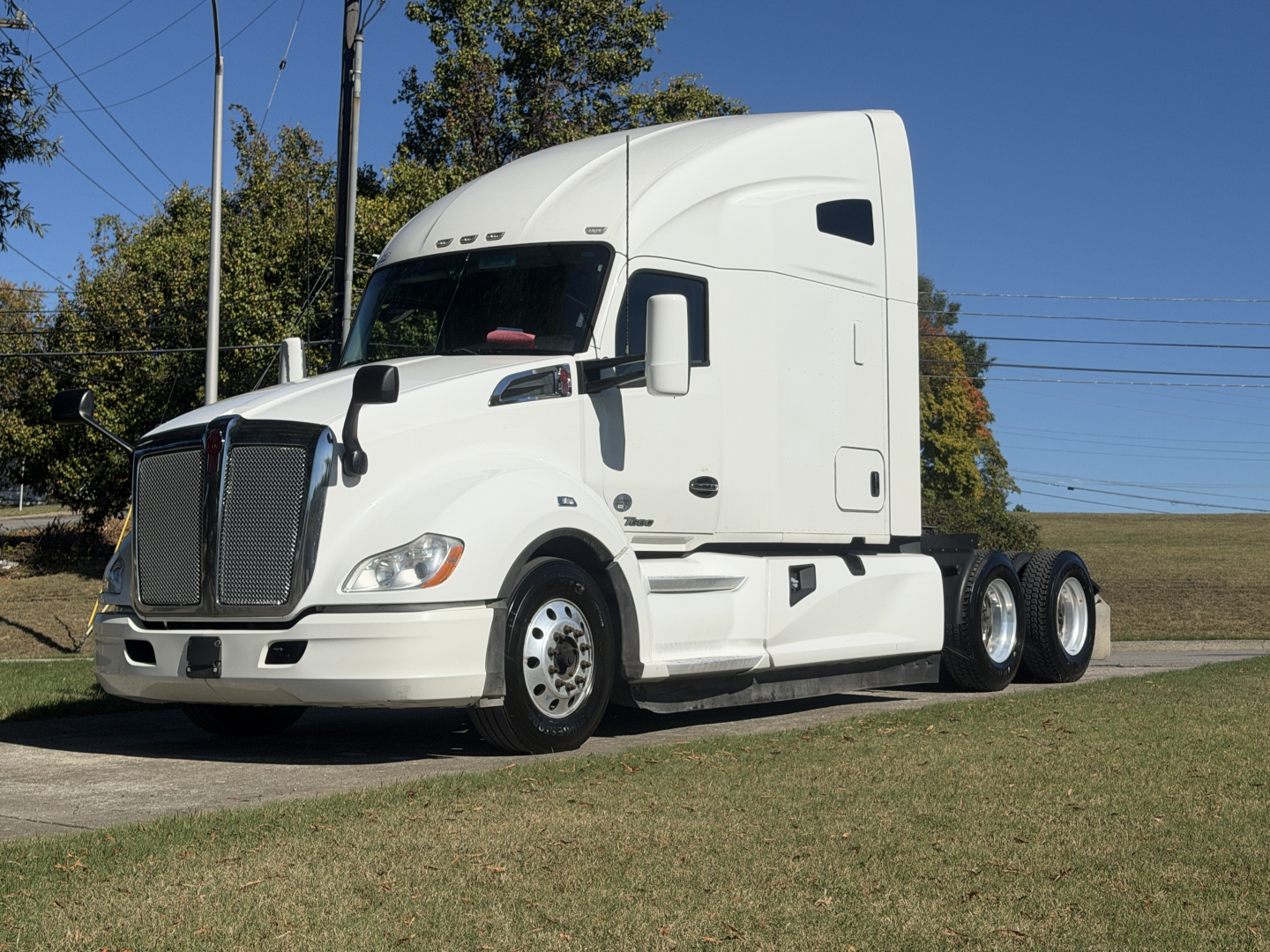 Kenworth T680 conventional sleeper tractor in white, front-left view, shows cab, grille, headlights, and dual rear axles.