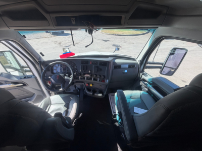 Kenworth T680 cab interior showing dashboard and steering wheel with seats and large windshield.