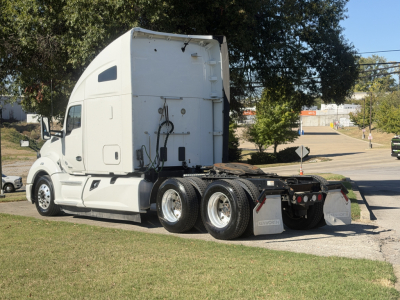 Kenworth T680 sleeper cab tractor in white, side view showing rear chassis and three axles, no visible damage, tires and wheels visible.