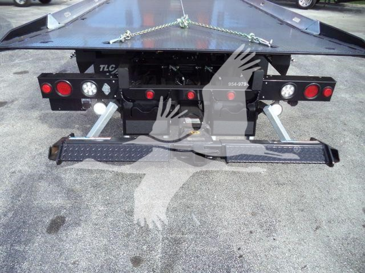 Rear view of a 2026 Mack MD6 rollback truck showing bumper, taillights, and rear hitch with chain and black steel steps.