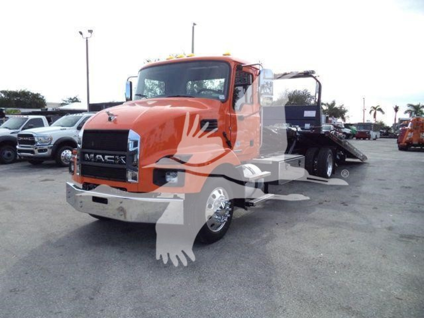 Orange 2026 Mack MD6 truck in a rollback configuration with a large grille, headlights, and a flatbed/dumping area; visible text includes 'MACK' on the grille and a graphic watermark across the image.