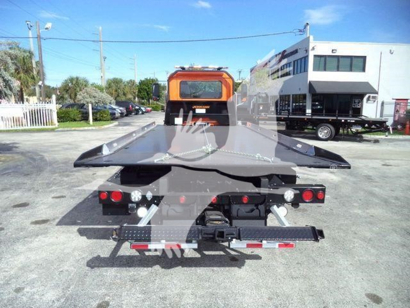 Flatbed tow truck in rear view showing bed and rear lights.