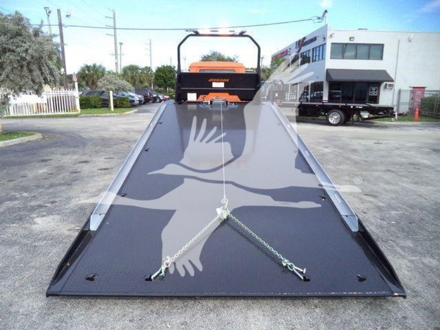 MD6 flatbed rollback truck deck with black surface and safety chains, rear view showing ramp and winch area.