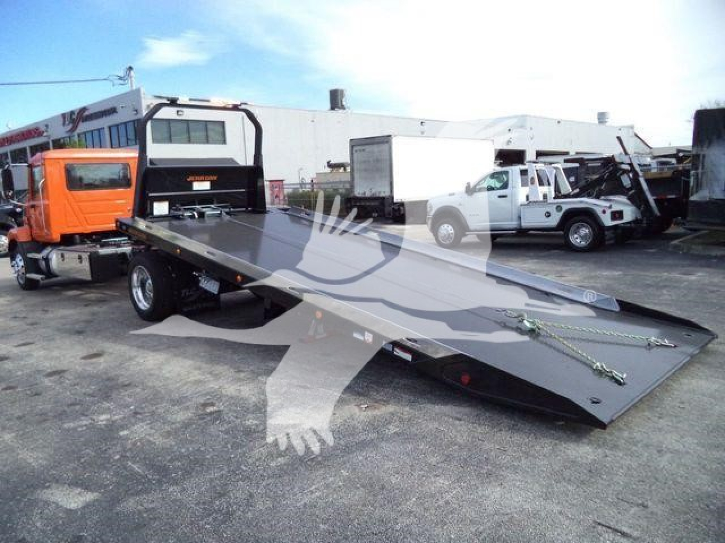 MD6 tow truck with flatbed in lowered position; no descriptive labels visible on flatbed. Vehicle lot background with other trucks.