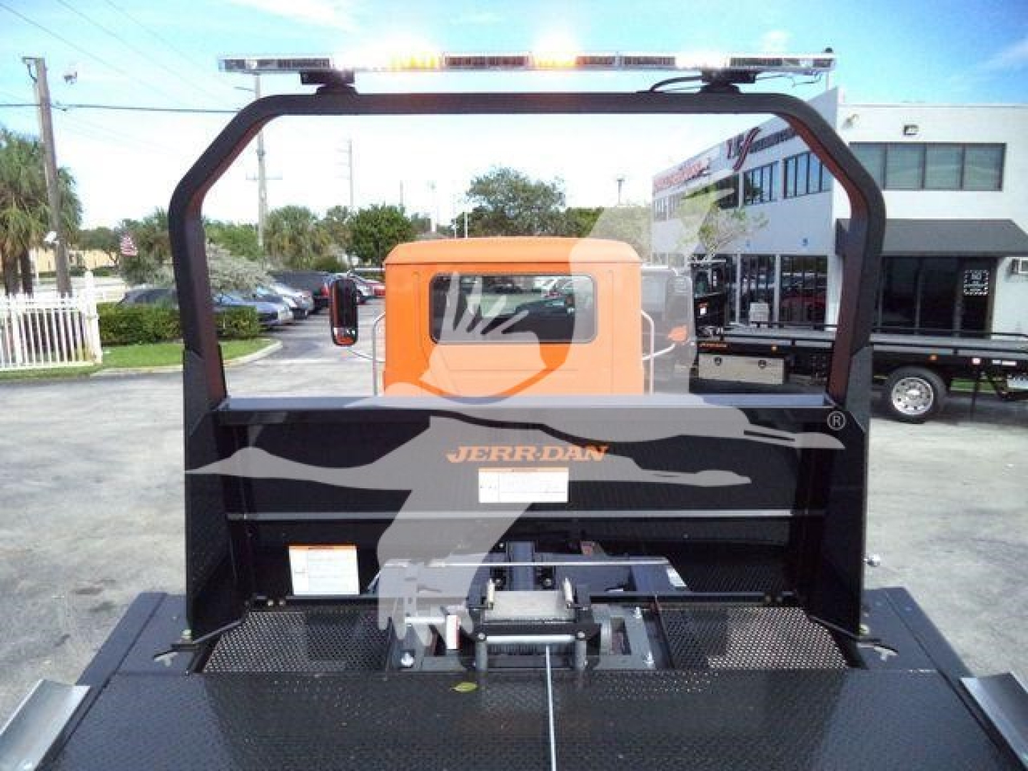 MD6 rollback truck with orange cab and black carrier frame, rear view showing hydraulic towing system and platform; 'Jerrdan' branding on rear panel.