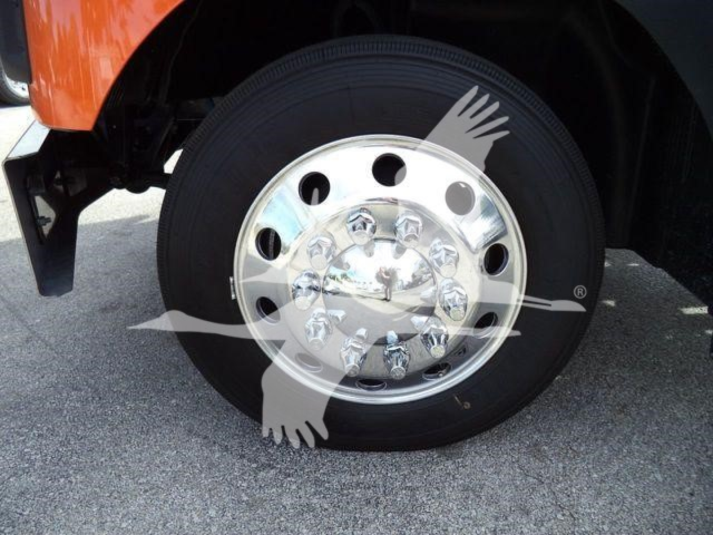 Mack MD6 wheel and chrome hubcap showing tire and part of orange truck body.