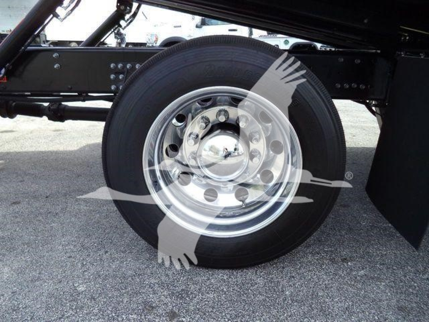 Truck chassis side view showing a large steel rim wheel with tire and black undercarriage components.