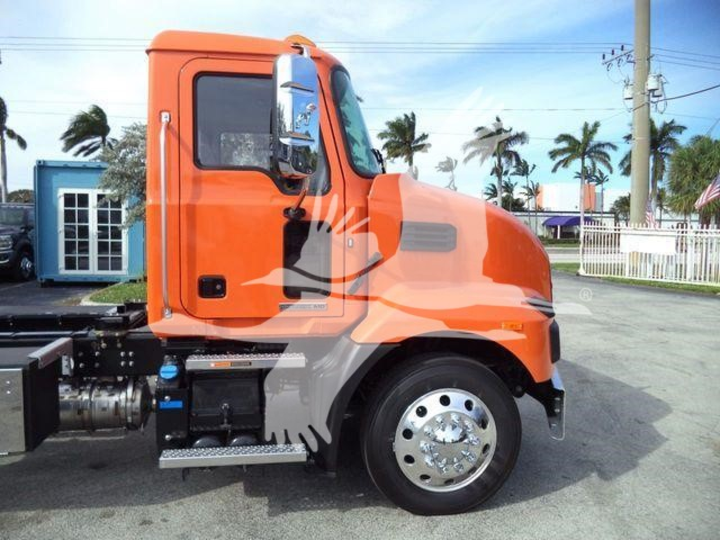 Orange Mack MD6 truck cab side view showing wheel and steps.