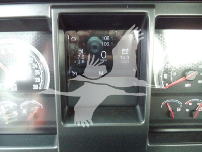Dashboard display in a Mack MD6 rollover truck showing digital gauge cluster with speedometer, voltage (14.3), and RPM readouts; central screen with numbers 106.1, 106.1 and N gear indicator.