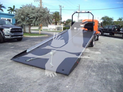 MD6 rollback truck with lowered loading ramp and orange cab, showing a flatbed surface for loading.