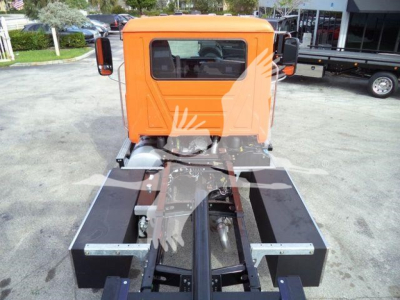 Orange Mack MD6 truck cab with a black chassis and coupling area; front view shows cab with rear window and side mirrors, no visible labels.