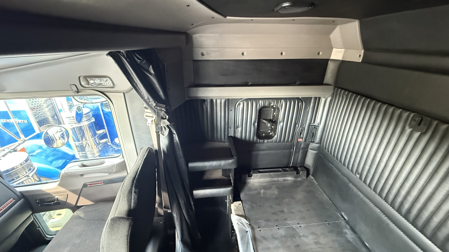 Kenworth W900 truck cab interior with sleeper area and ribbed metal walls, cargo area floor visible.