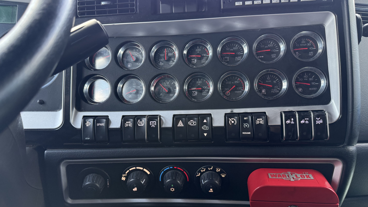 Kenworth W900 dashboard with multiple gauges and switches, heater controls, and a red WorkTool brand item in the lower area.