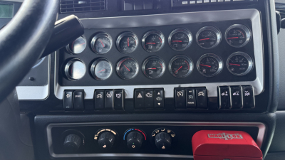 Kenworth W900 dashboard with multiple gauges and switches, heater controls, and a red WorkTool brand item in the lower area.