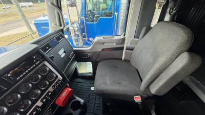 Kenworth W900 truck interior cab view showing steering column, dashboard, and driver seat.