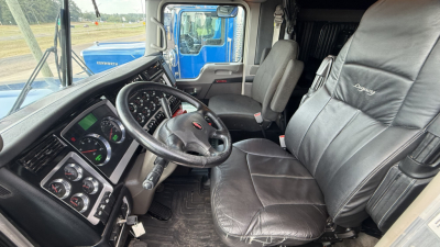 Kenworth W900 truck interior showing steering wheel, dashboard gauges, and black leather seats in a sleeper cab.
