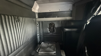 Kenworth W900 sleeper cab interior showing ribbed metal side panels and a small rectangular rear window opening.