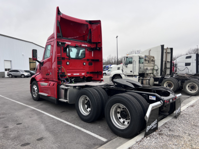 Volvo VNL64T300 tractor in red cab shown from side with exposed chassis and dual rear axles. Visible text includes nothing legible on decals from this angle.