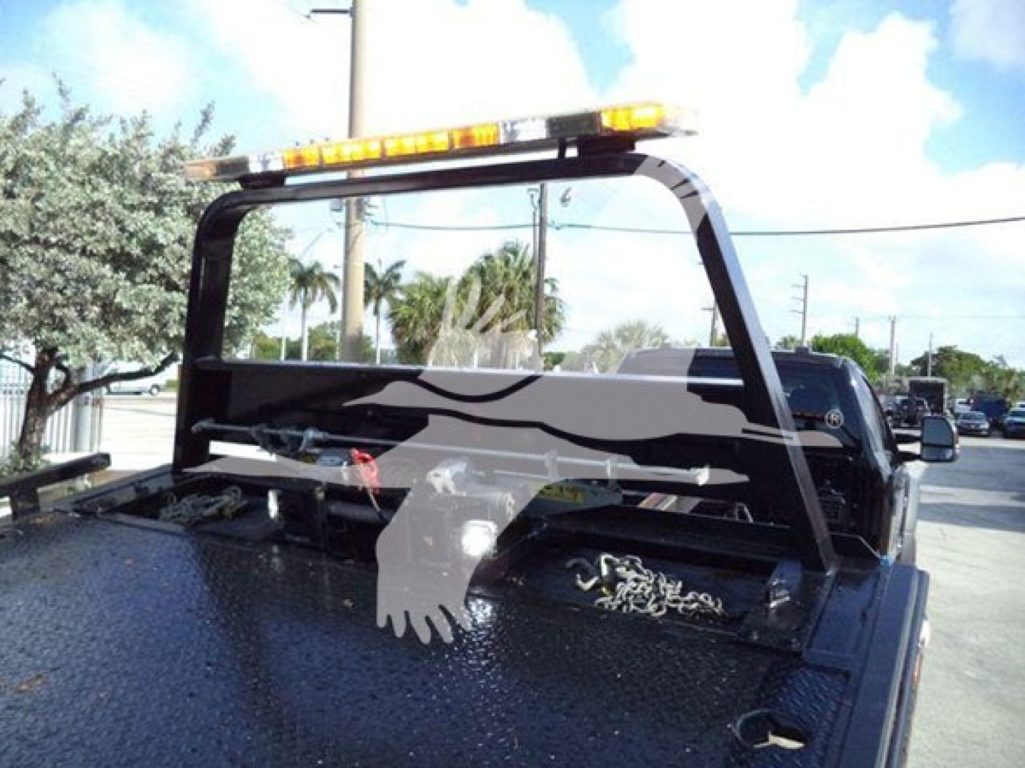 Truck bed of a 2022 Ford F600 rollback showing a safety bar and reflective light bar on top with a patterned back grid.