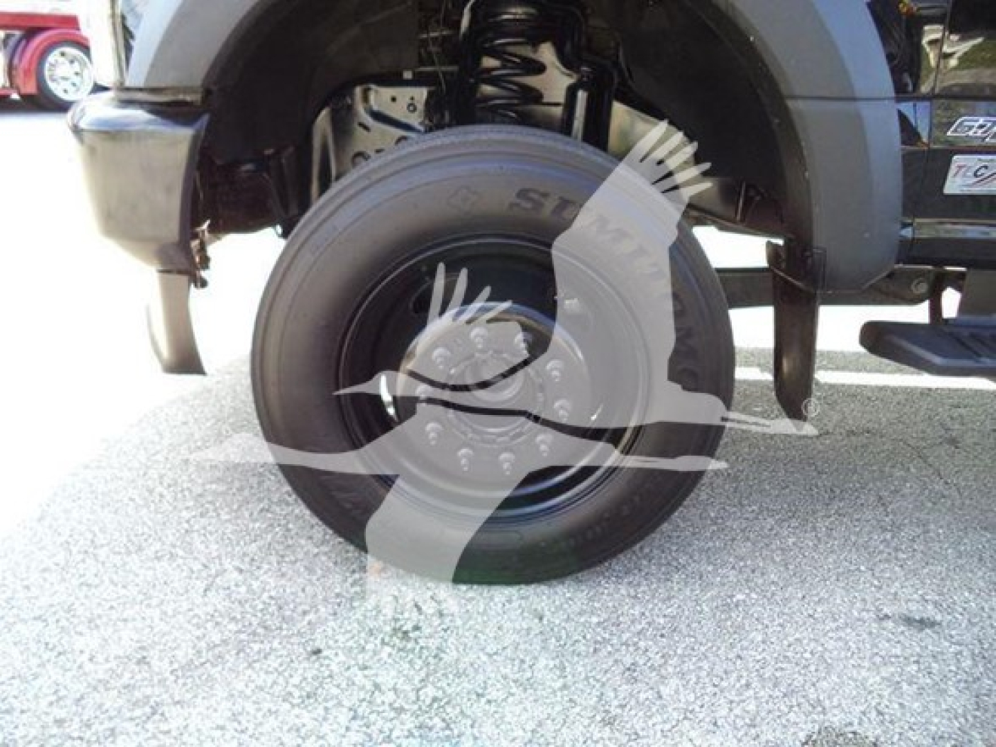 Ford F600 front wheel and suspension view showing tire and fender with hydraulic lines and wheel well.