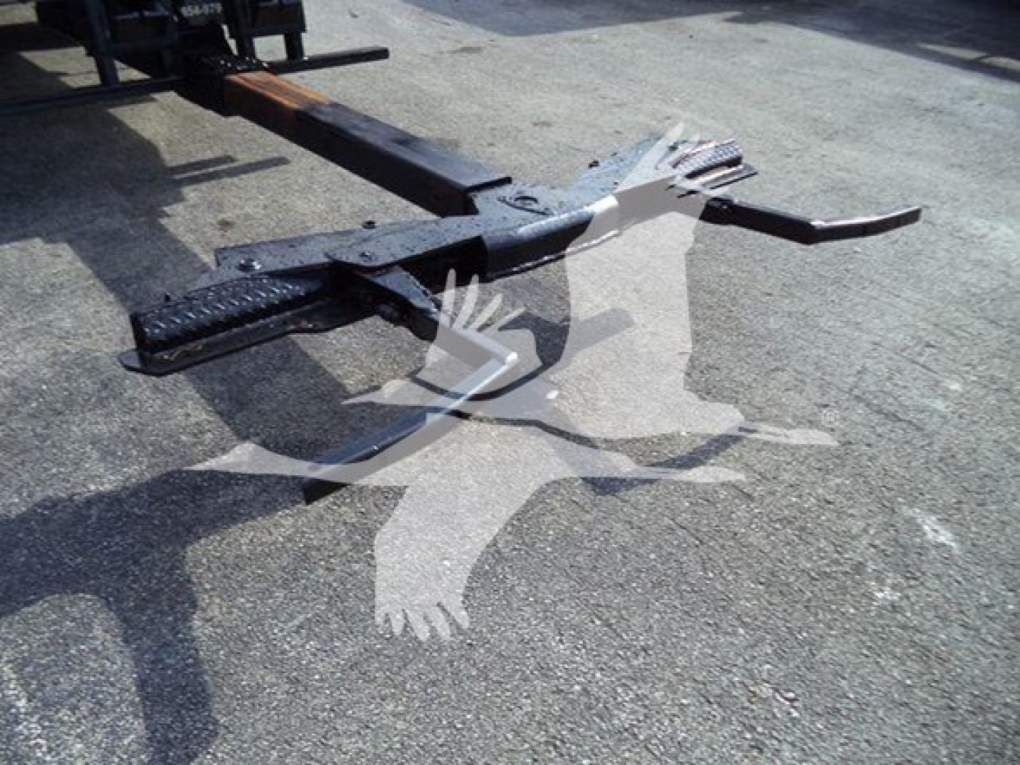 Truck equipment hitch assembly and framework with black steel components resting on asphalt.