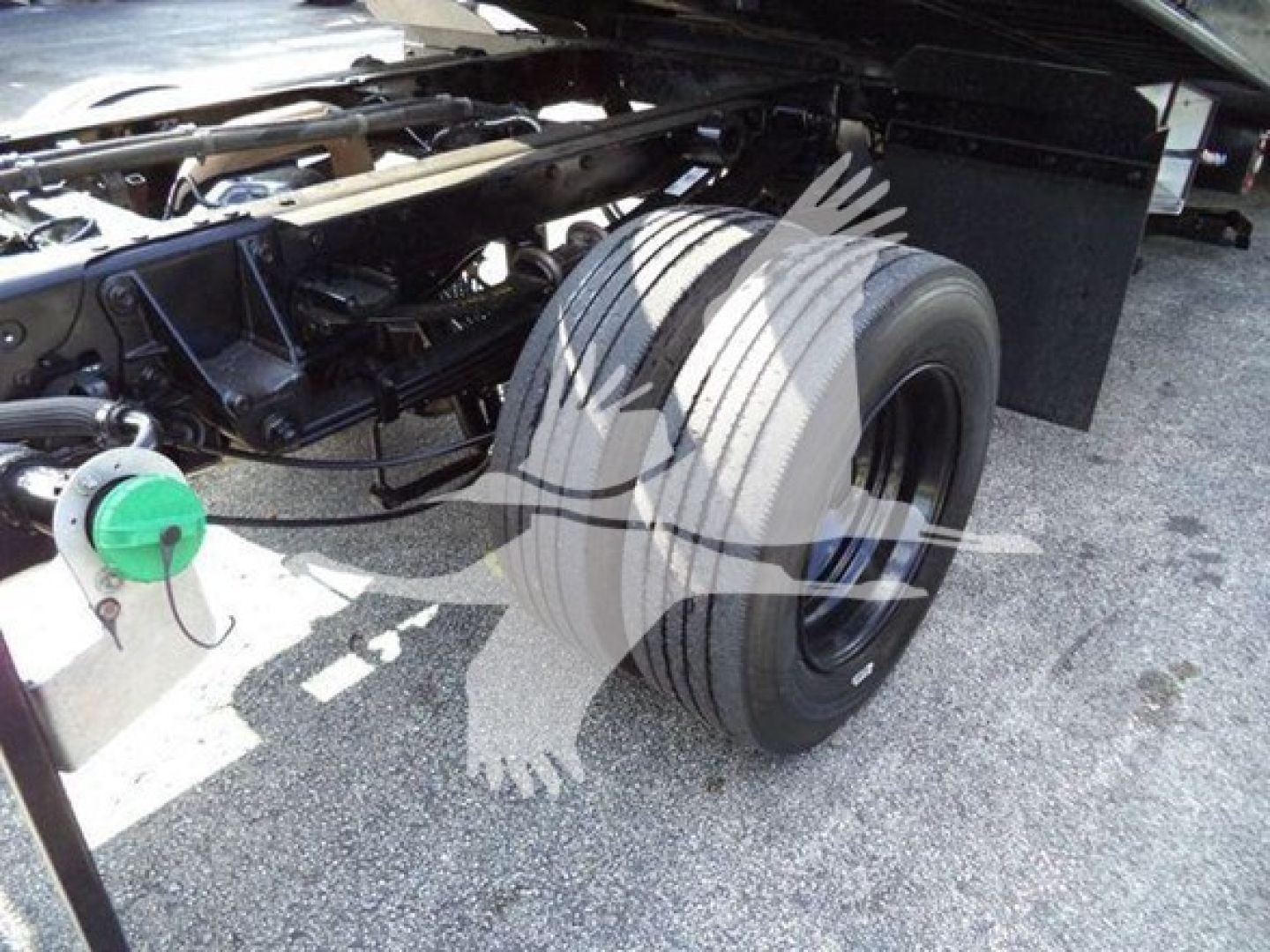 Truck chassis and dual rear tires of a 2022 Ford F600 rollback truck showing a green hose reel and exposed frame components.