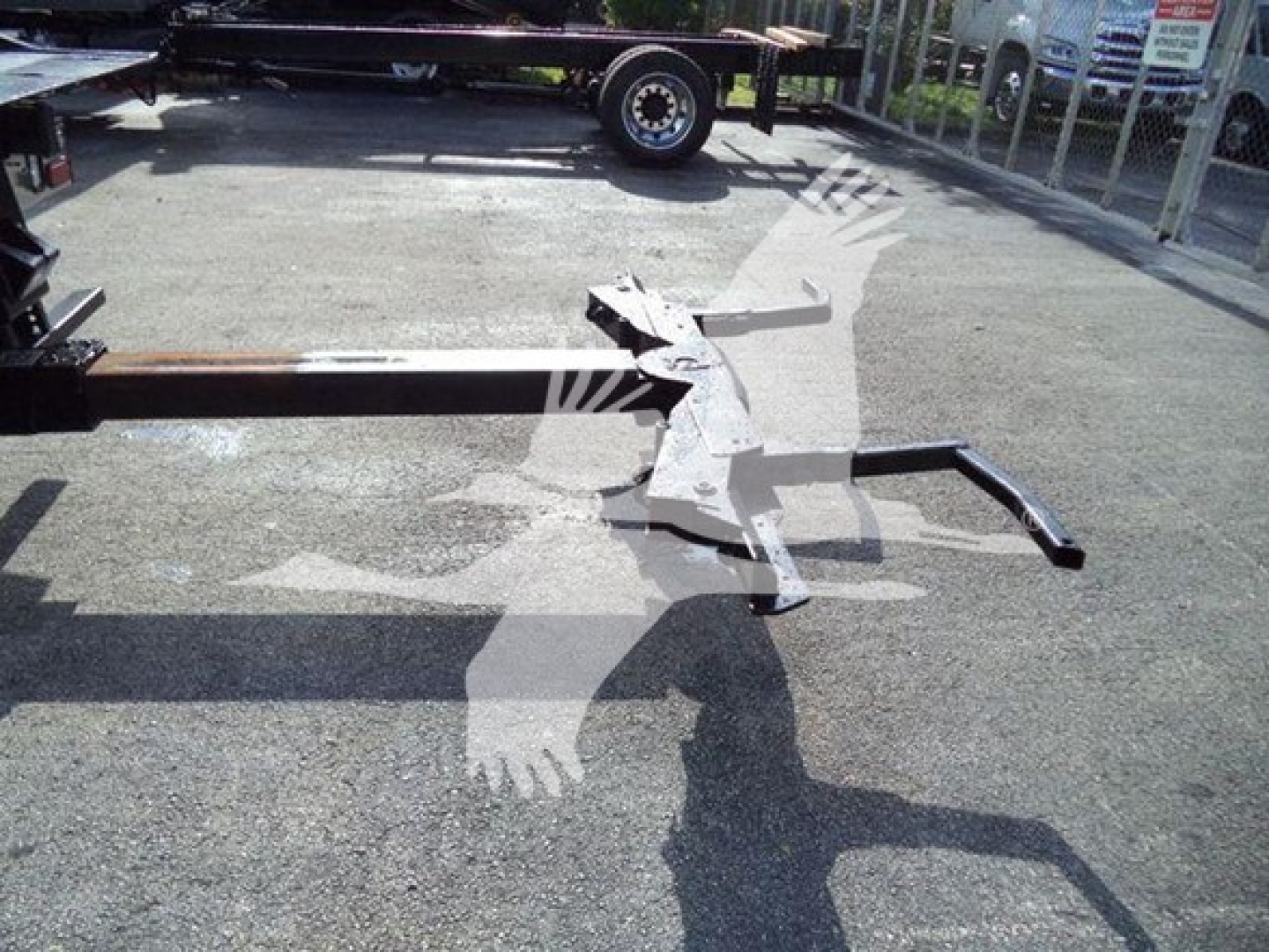 Hydraulic rollback equipment and mounting arms laid on pavement.