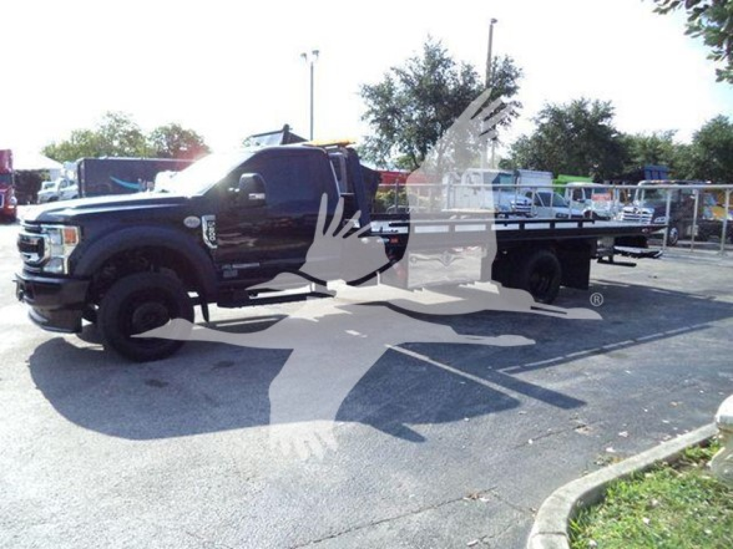 Tow truck in a parking lot with a rollback bed attached to a Ford F-600 pickup, front cab visible, stock number T16523.