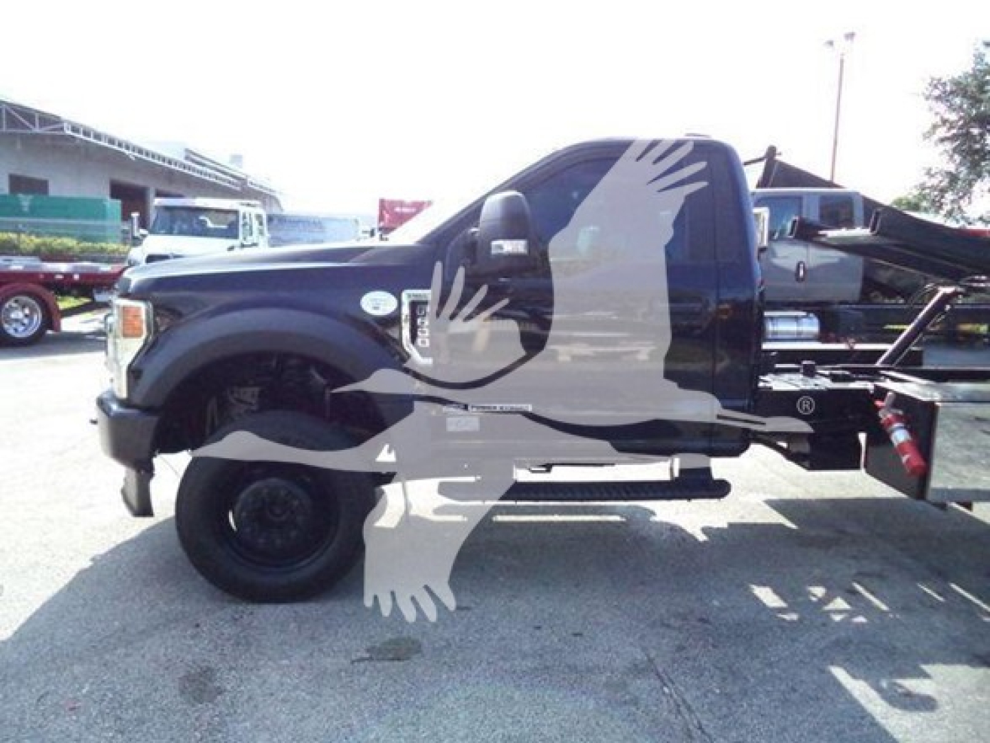 Ford F-600 rollback truck side view showing cab and chassis with extended hydraulic bed; no visible text legible on the vehicle.