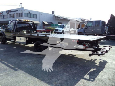 Flatbed tow truck with extended bed on a Ford F-600 chassis, rollback configuration, side view showing dual rear wheels and towing equipment.