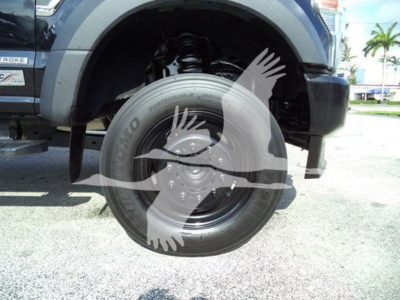Ford F-600 rollback truck front wheel and suspension visible in wheel well with tire and hub, partially showing front fender and bumper.