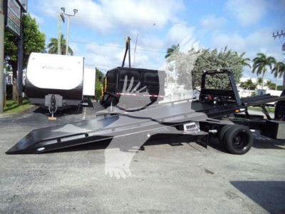 Chassis of a rollback truck with a flatbed and tool cabinets, showing a low-angle view of the bed and wheel.