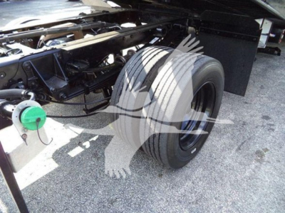 Truck chassis and dual rear tires of a 2022 Ford F600 rollback truck showing a green hose reel and exposed frame components.