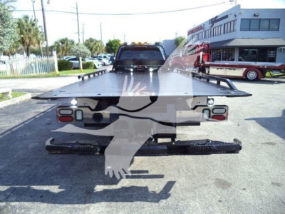 Tow truck rollback platform showing rear view with taillights and hydraulic ramps.