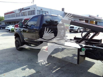 Ford F-600 rollback truck with hydraulic bed, side view showing wheel, cab, and flatbed apparatus.