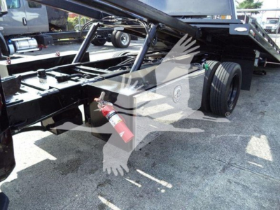 Truck chassis with hydraulic rollback frame and wheel; visible label area shows a fire extinguisher mounted underframe.