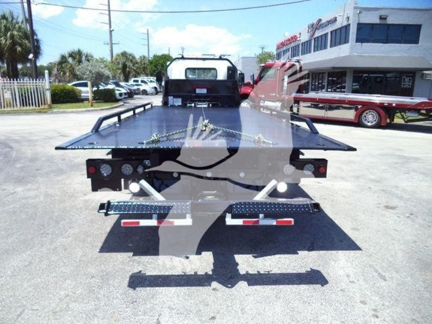 Isuzu NPRR 2025 rollback truck bed shown from rear with hydraulic tilt flatbed and taillights.
