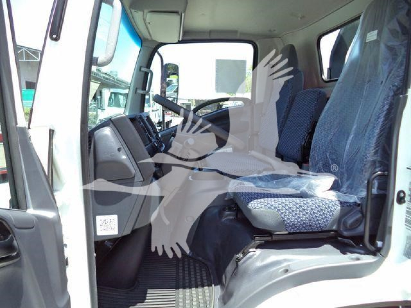 Isuzu NPRR cab interior of a new rollback truck showing steering wheel, dashboard, driver seat, and passenger seat with plastic seat covers.
