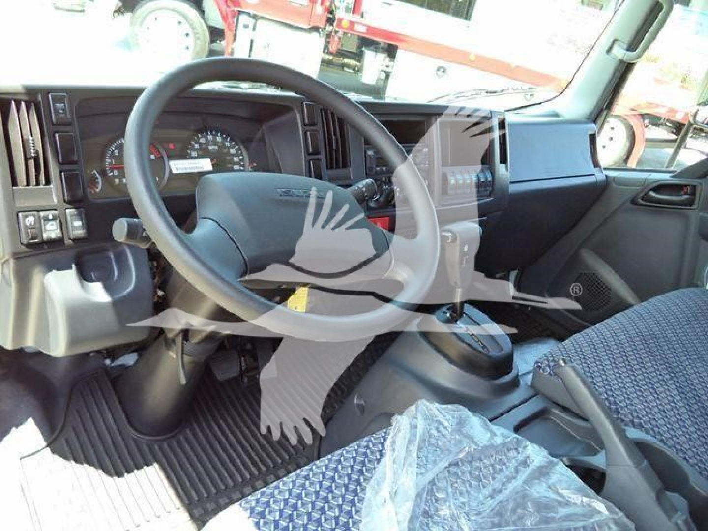 Isuzu NPRR cab interior showing steering wheel and dashboard with center console and driver’s seat; stock NRRGAS22XLP rollback truck interior.