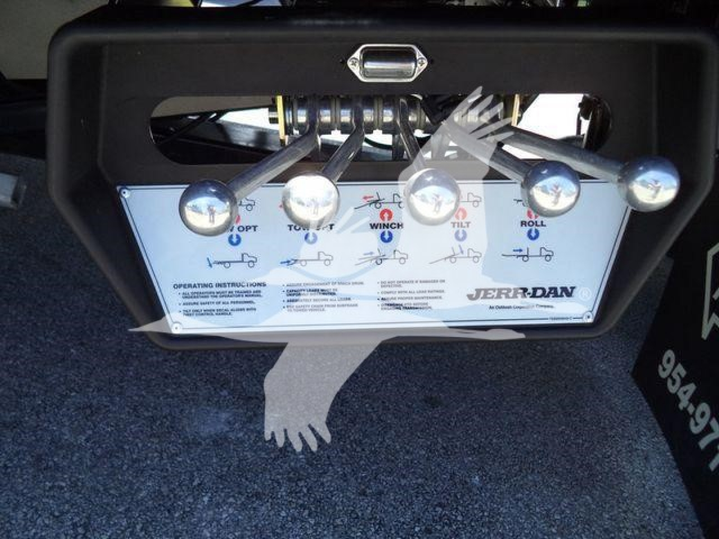 Isuzu NPR truck rollback control panel with levers and labels such as OPt, TILT, WINCH, TILT, ROLLO. Close view of control panel and levers.