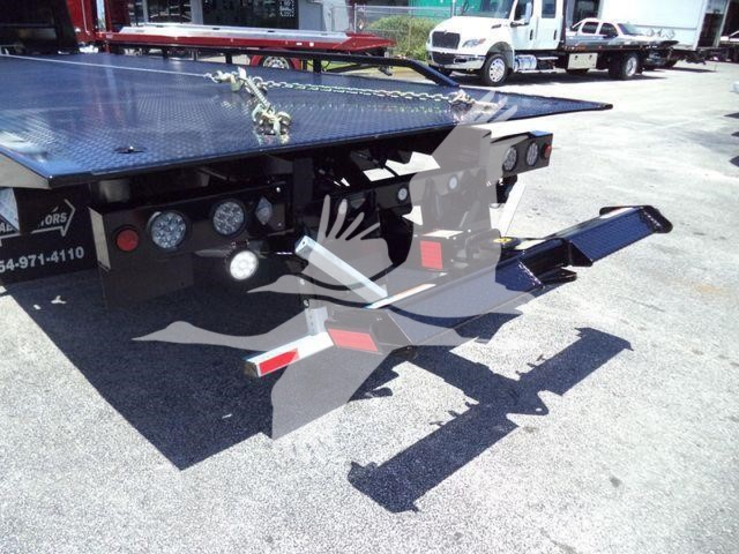 Isuzu NRR rollback truck rear view showing hydraulic ramp and platform with metal diamond plate surface.