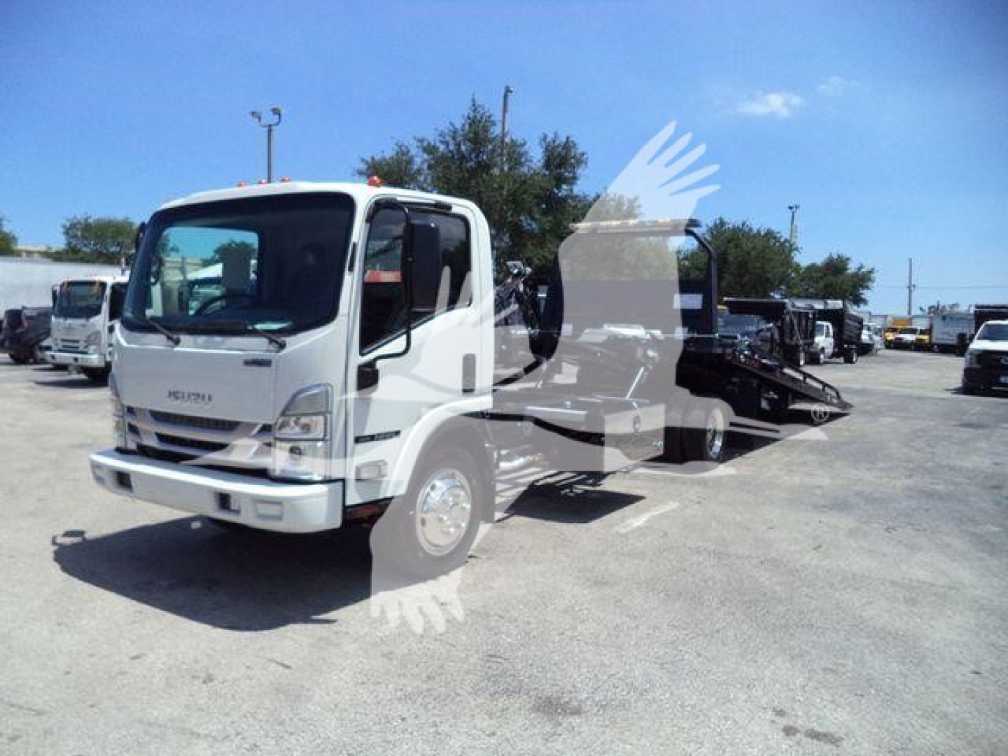Isuzu NPRR truck in a dealership lot showing a rollback wrecker body and white cab.