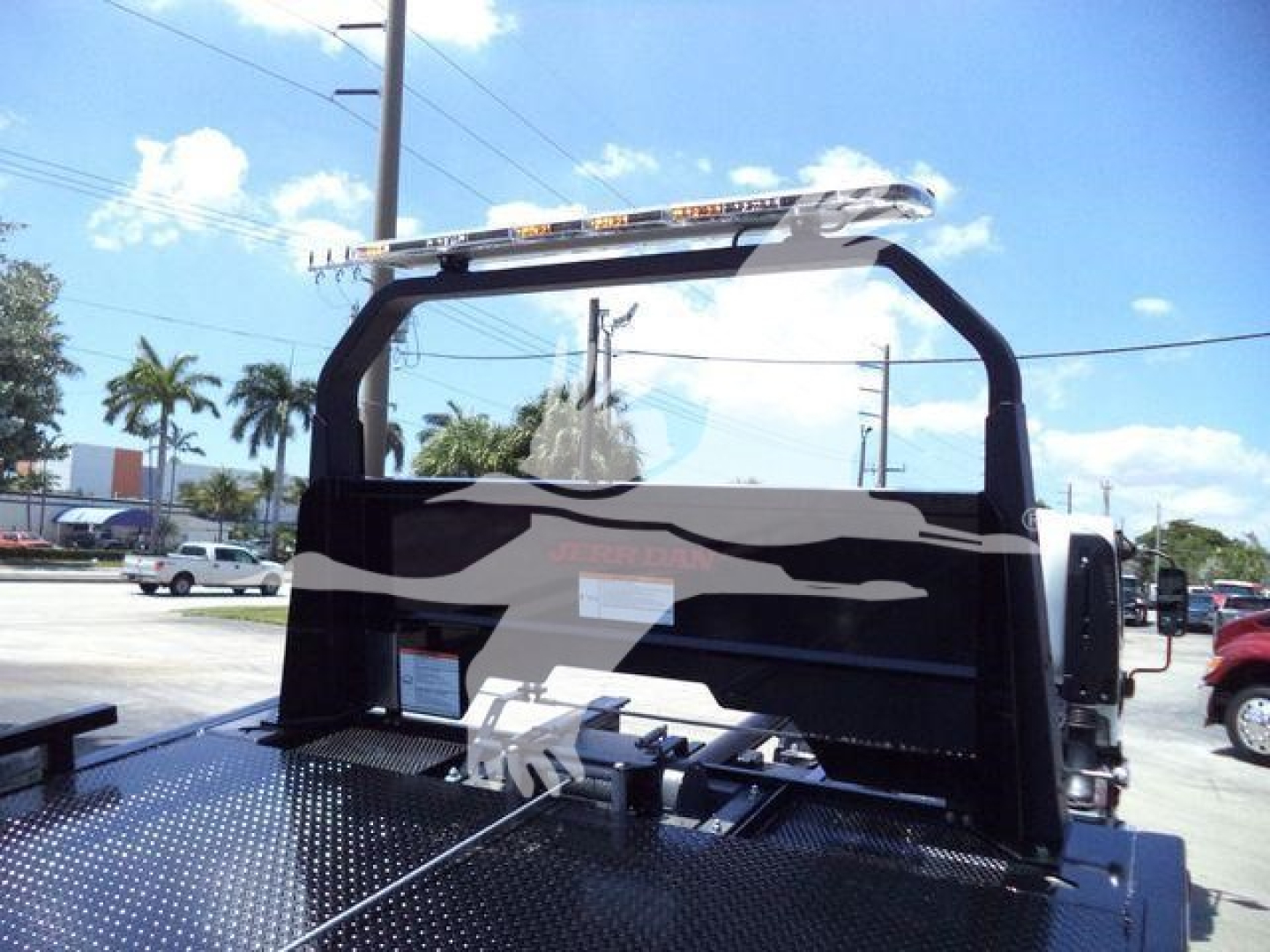 Isuzu NR rear view of rollback truck bed with flame graphics, metal deck, and towing hook area.