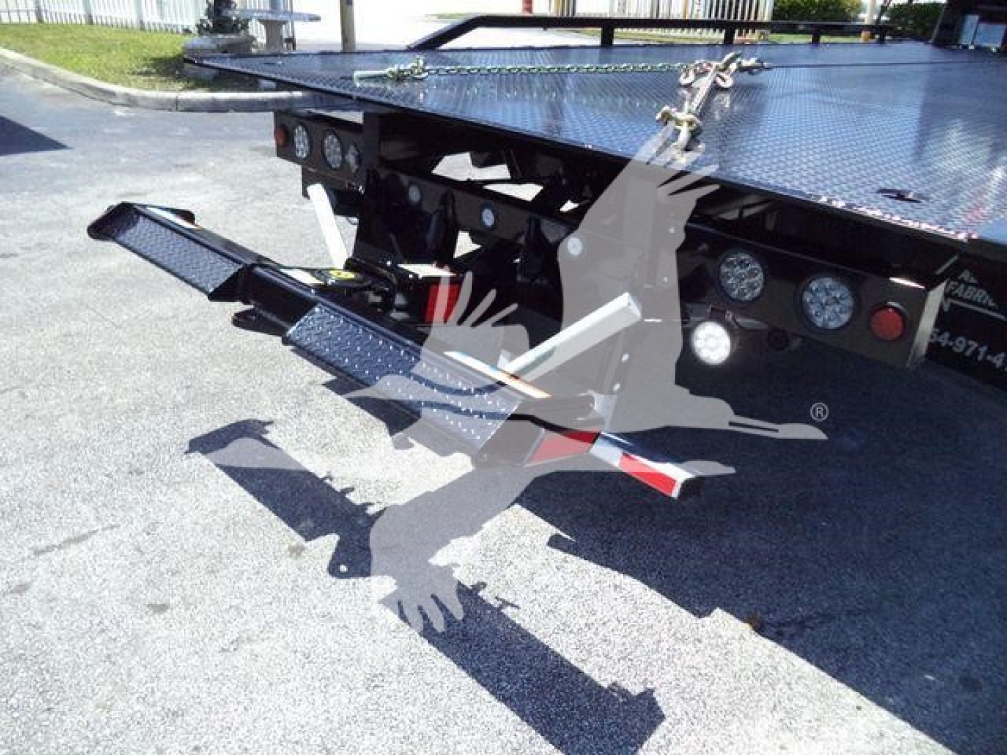 Isuzu NRR rollback truck bed with hydraulic lift and metal diamond-plate surface; rear section showing platform and support ramps.