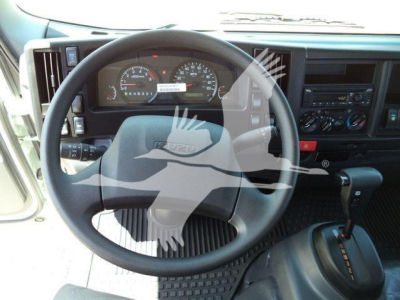 Isuzu NPRR cab interior showing steering wheel, dashboard gauges, and center console with gear shifter.