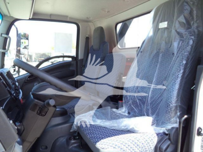 Isuzu NPRR truck cab interior view showing steering wheel, driver seat covered in protective plastic, and passenger seat with fabric pattern.