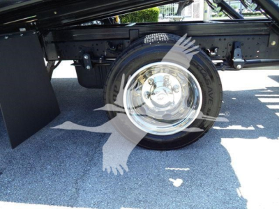 Isuzu NPRR truck chassis showing front wheel and suspension components with chrome hubcap.