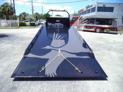 Isuzu NRRGAS22XLP rollback truck bed with a black diamond plate surface and tie-down chains, rear view.