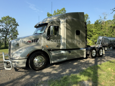 Semi truck tractor unit with sleeper cab, silver color, front bumper guard, dual rear axles, large fuel tanks, chrome wheels; visible text on image watermark not legible.