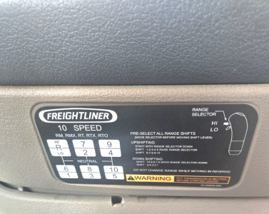 Freightliner gear shift panel showing range selector with digits 1-8 and letters R N with 10 speed emblem and warning label.